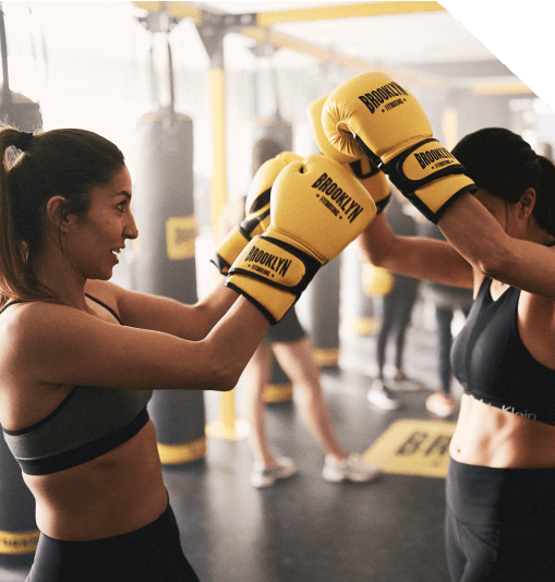 Dois fitboxers encostam as luvas após um treino